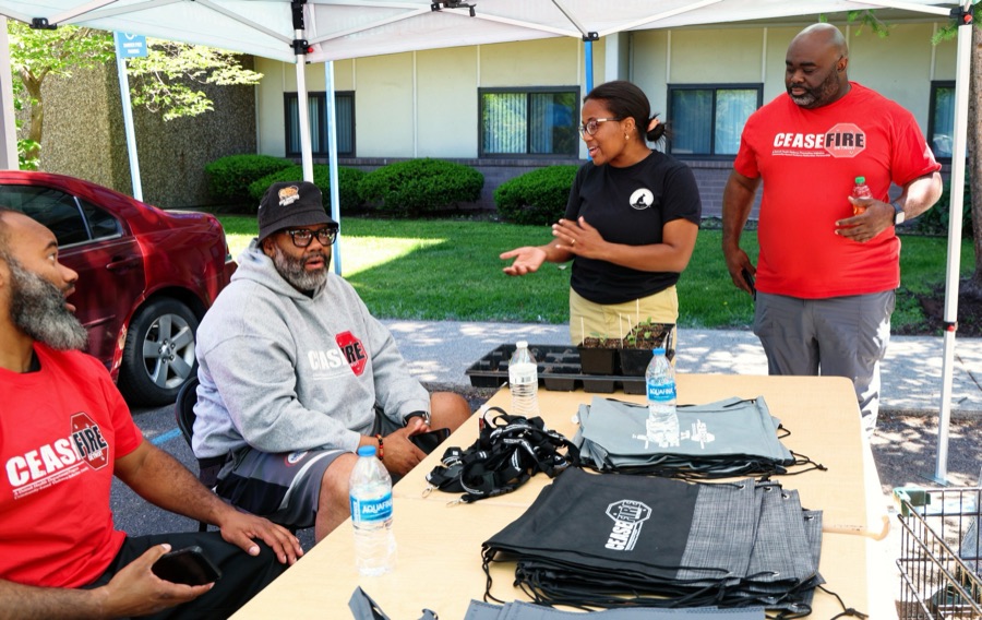 Tiffany Carey Jones talking with community members at a Ceasefire Detroit table, seedling trays on the table beside them