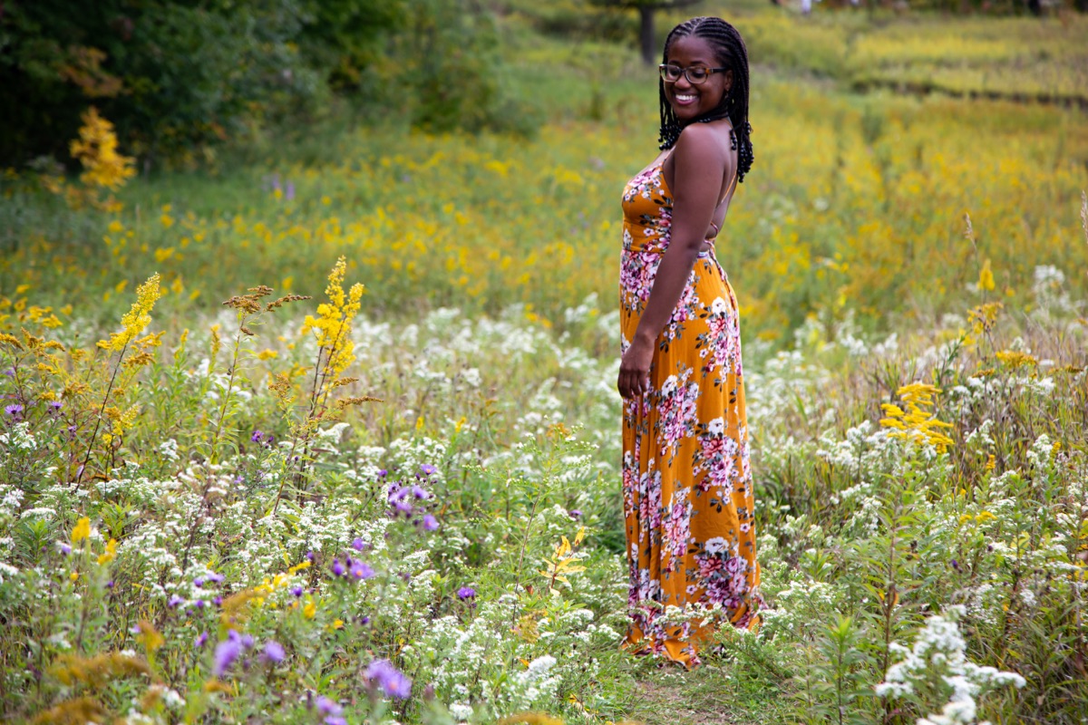 Tiffany Carey Jones standing and smiling in a wide wildflower meadow, looking back over her shoulder